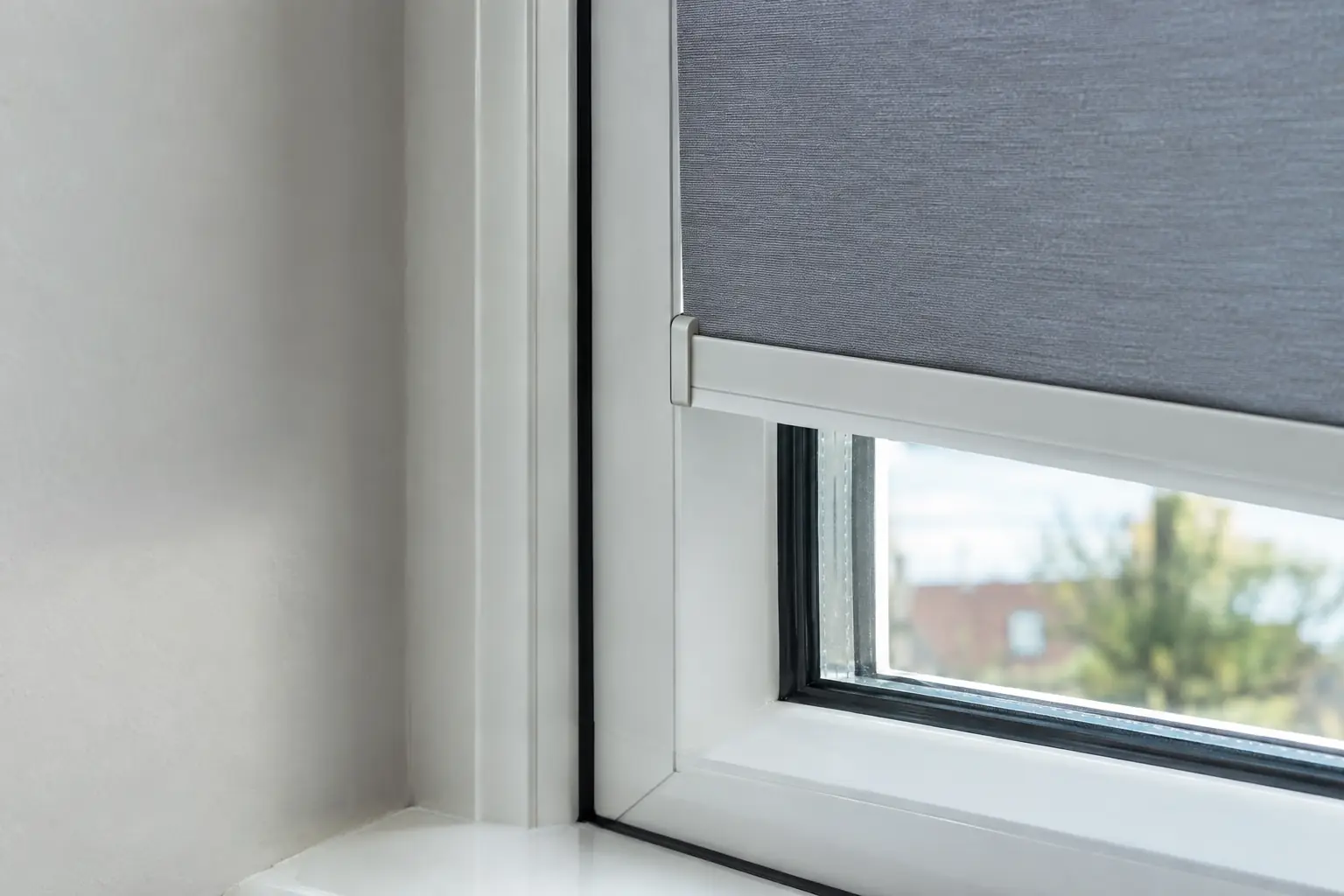an extreme close-up of the corner of a white uPVC window where the slim frame of a blind clips neatly into the rubber gasket beside the glass, no screws or drill holes anywhere on the window frame